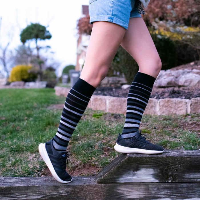Knee-high socks with a graduated stripe pattern, worn with denim shorts and black athletic shoes.