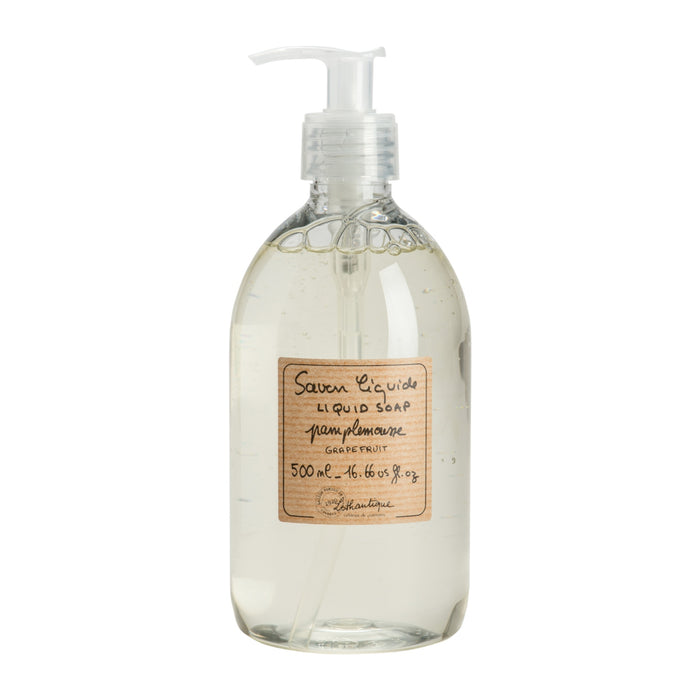 Clear glass bottle of liquid soap with a pump and wooden label on a white background