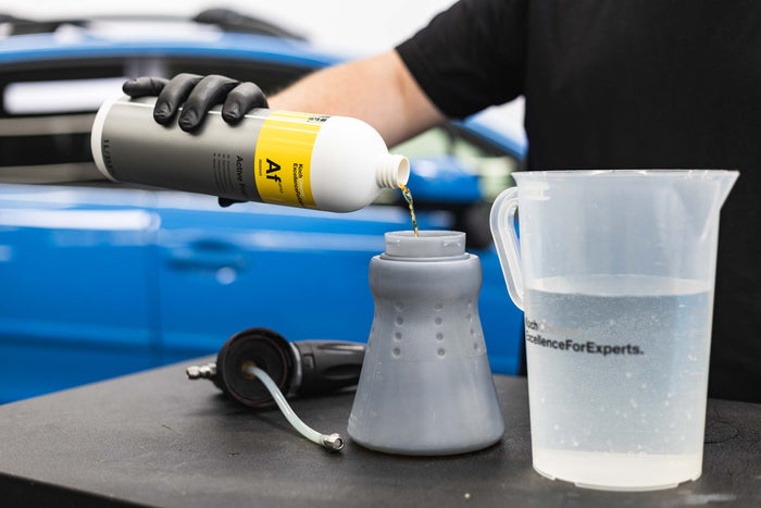 A person filling an iK foam sprayer filled with KochChemie Active Foam.