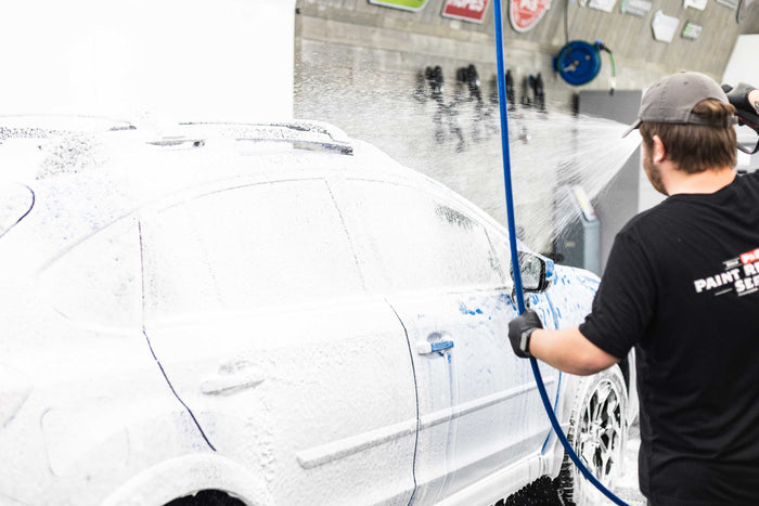 A person washing a car with an iK foam sprayer filled with KochChemie Active Foam.