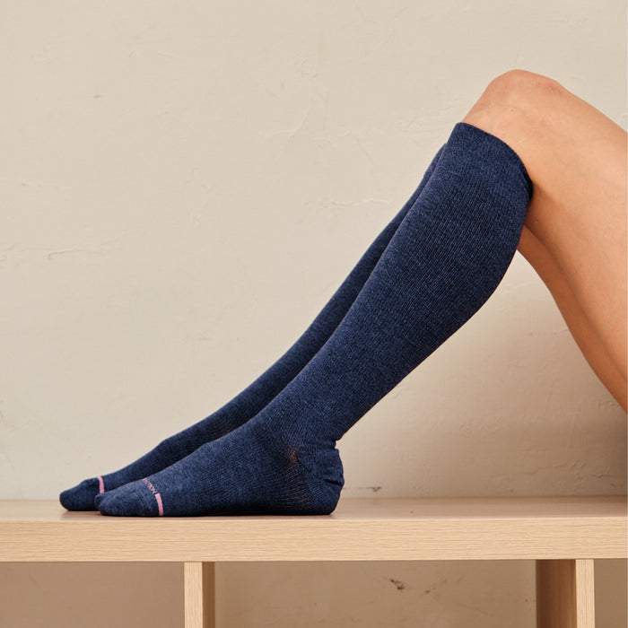 Knee-high compression socks in dark blue with a textured pattern and pink accents on the toes.