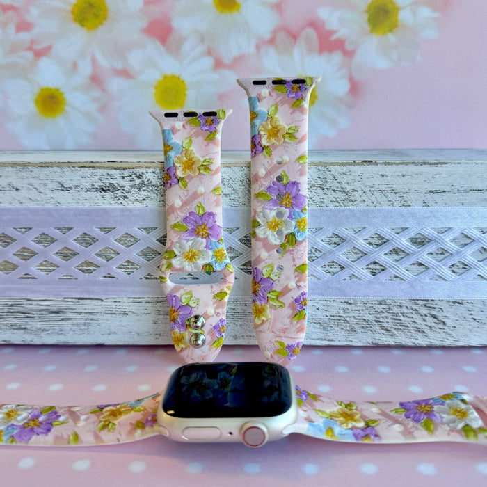 Blushing Bouquet Apple Watch band with watercolor flowers in purple, blue, yellow, and white on soft pink background