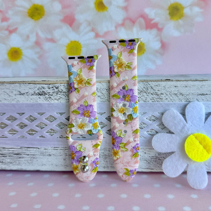 Blushing Bouquet Apple Watch band with watercolor flowers in purple, blue, yellow, and white on soft pink background
