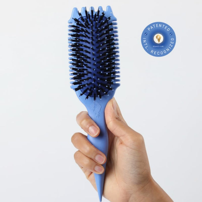 Blue detangling brush for curly hair with patented design, held in hand