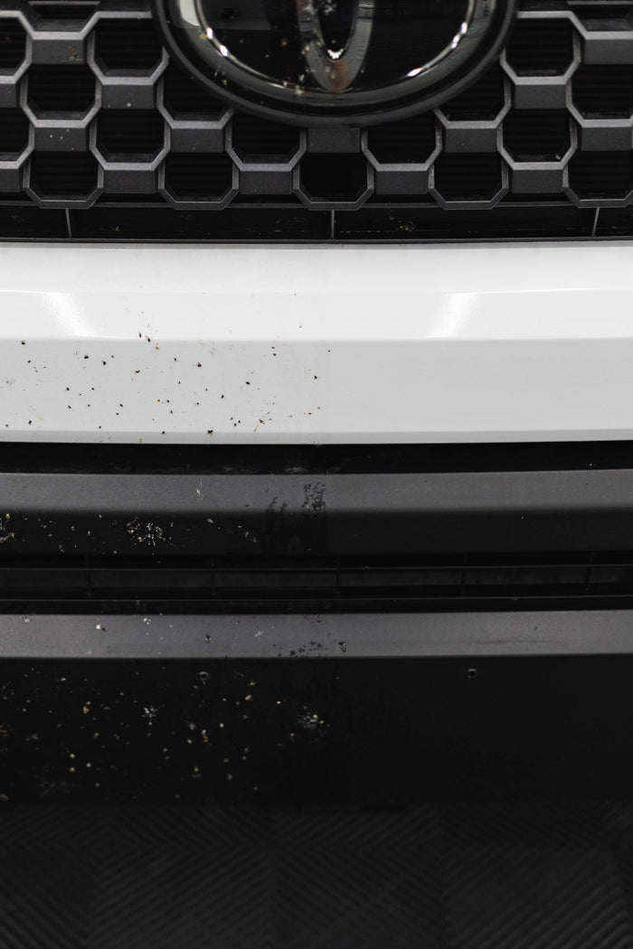 Close-up of a car grille with before and after of using P&S Bug Off.