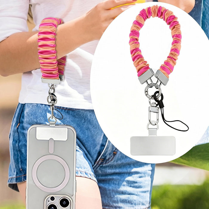 Pink and orange striped Candy Citrus Stripes scrunchie phone wrist strap clipped to the matching hot pink and citrus orange striped Wavy Luxe iPhone case, styled on a playful pink and orange heart print background.