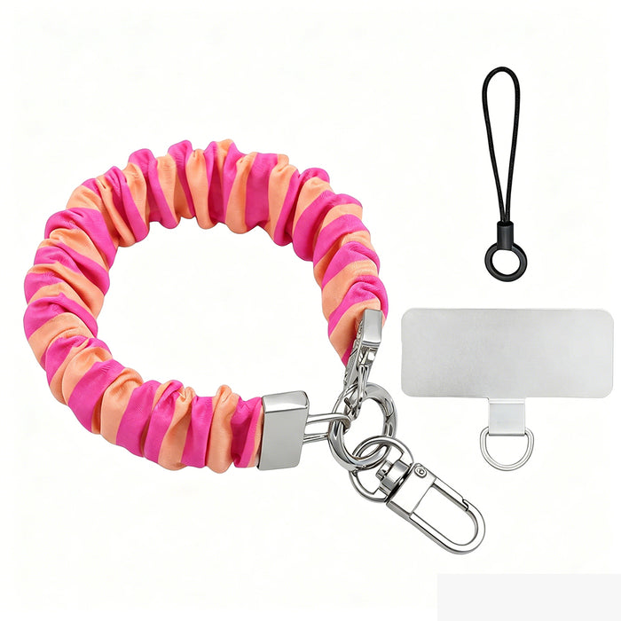 Pink and orange striped Candy Citrus Stripes scrunchie phone wrist strap clipped to the matching hot pink and citrus orange striped Wavy Luxe iPhone case, styled on a playful pink and orange heart print background.