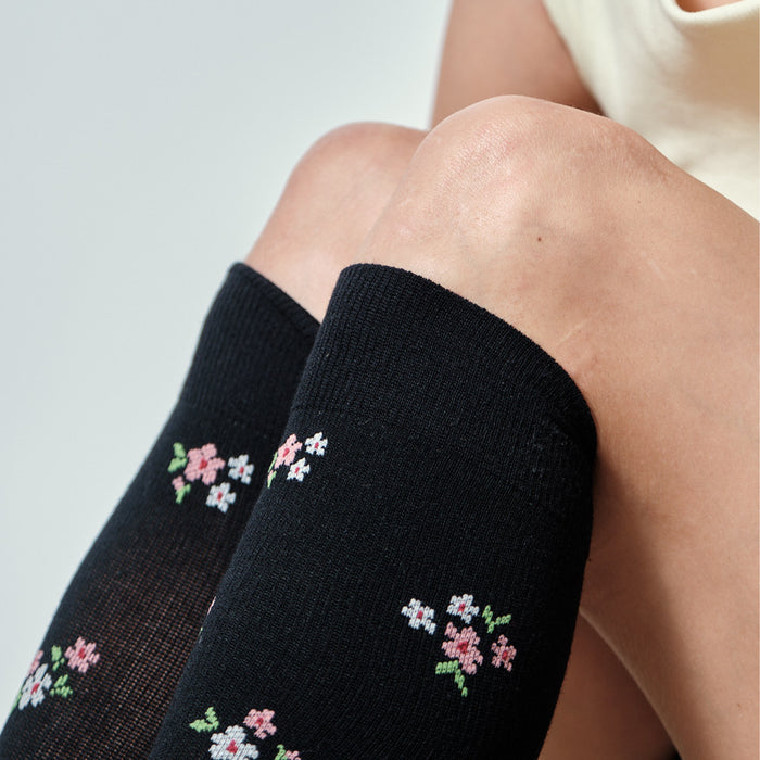 Knee-high black socks with a floral pattern, resting just below the knees.