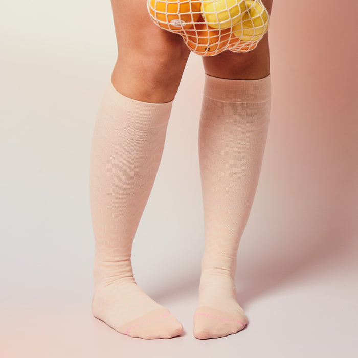 Knee-high compression socks in a light pink hue with a chevron pattern and contrasting toe detail.