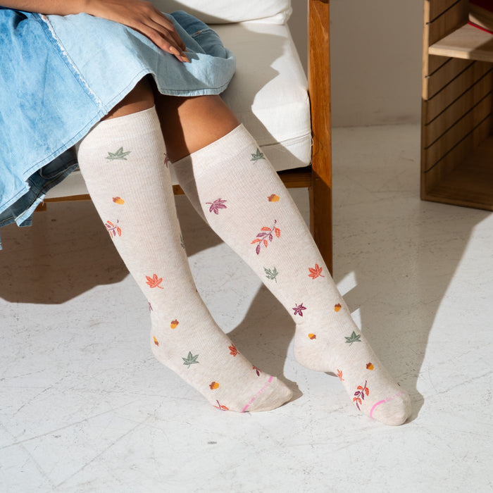 Knee-high compression socks with a light background and colorful leaf patterns.