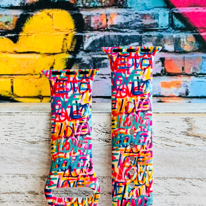Love Riot Apple Watch band with colorful graffiti "LOVE" text in red, pink, yellow, blue, and turquoise with street art backdrop