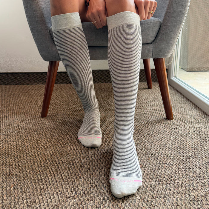 Knee-high compression socks with a microstripe pattern, featuring a light gray color and pink accents.