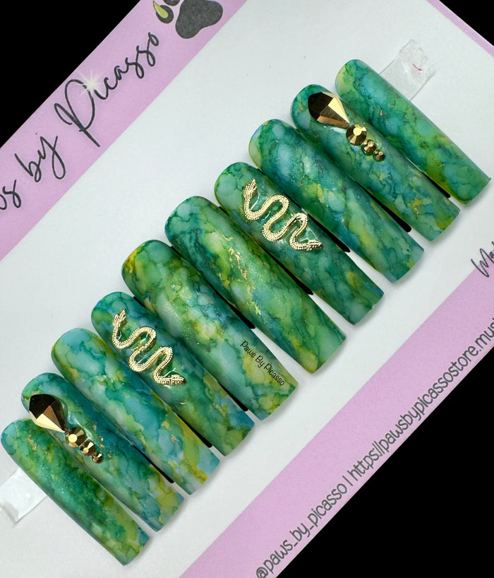 Set of green marbled hair clips with gold accents on a white and purple background