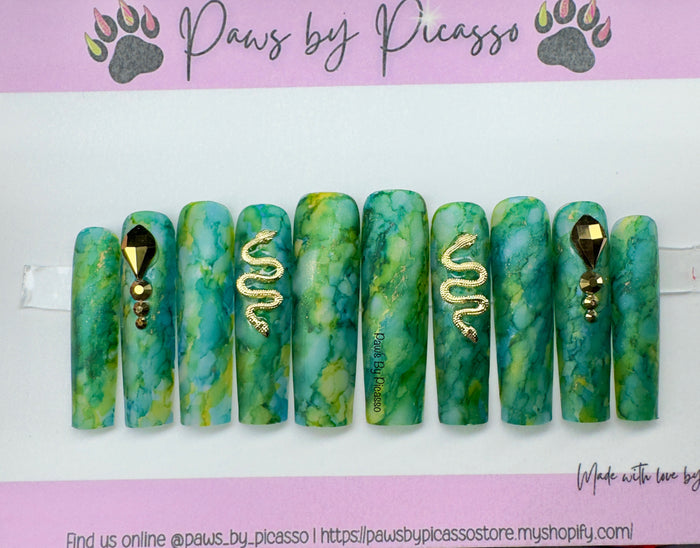 Set of green marbled nail art designs with gold accents on a white background, branded 'Paws by Picasso'.