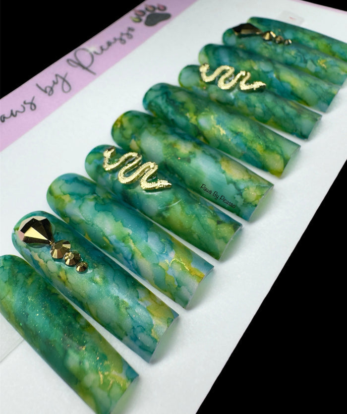 Green marbled nail art designs with gold accents on a white background