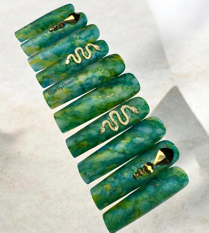 Set of green marbled hair ties with gold accents on a light background