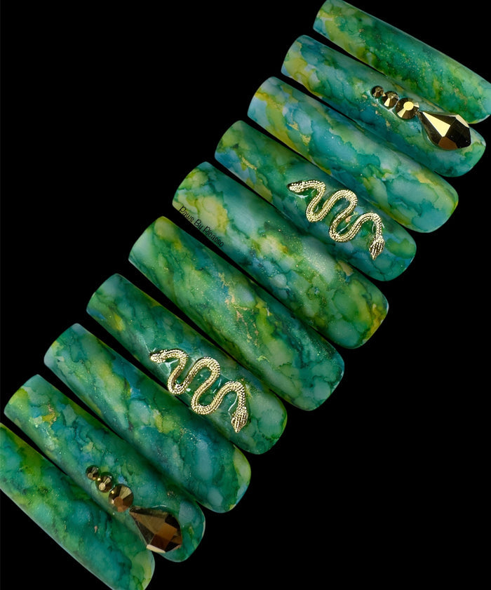 Set of green marbled hair ties with gold accents on a black background