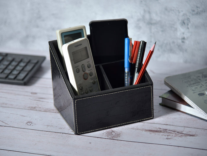 Rectangular black croc-texture remote holder with three compartments, holding remotes and pens