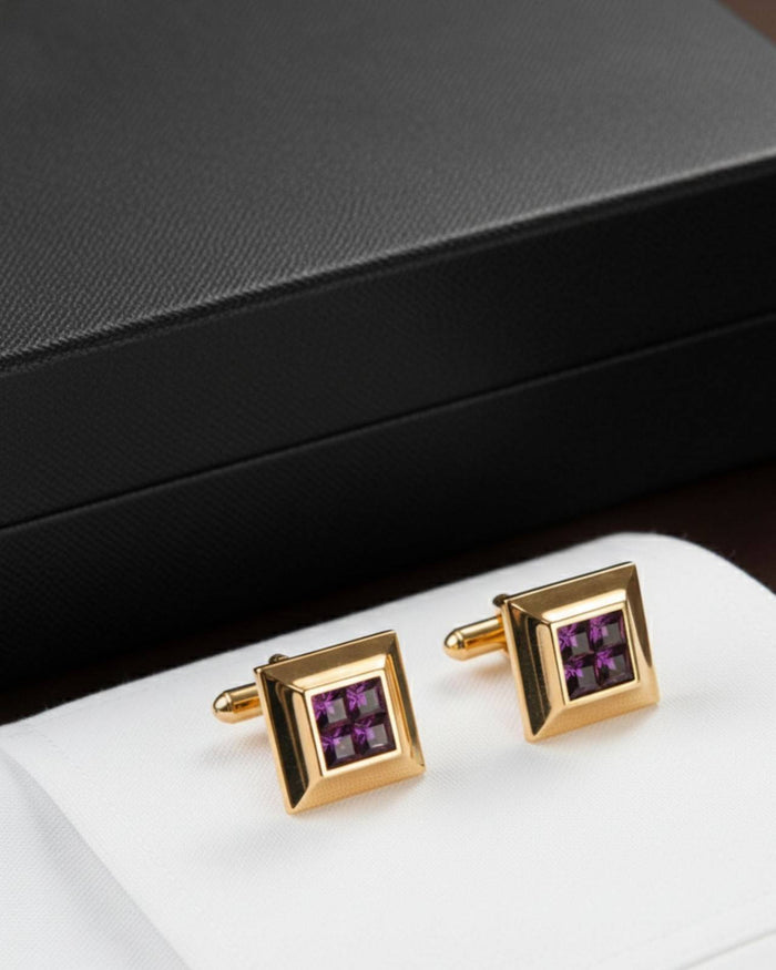 Gold tone square cufflinks with purple crystal centers on white surface
