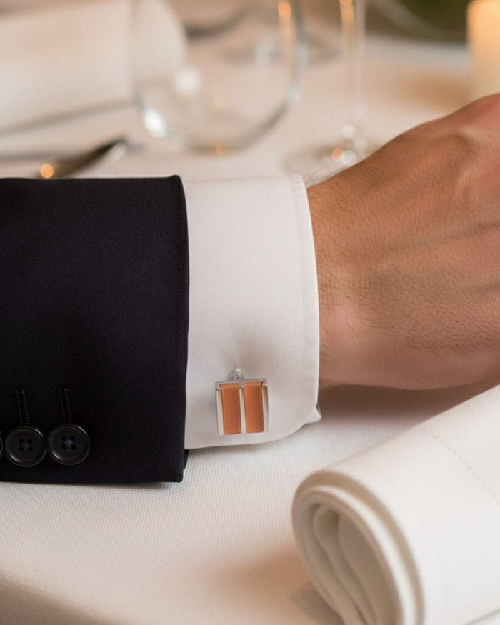 Rectangular silver cufflinks with orange dual stripe inlay on shirt cuff
