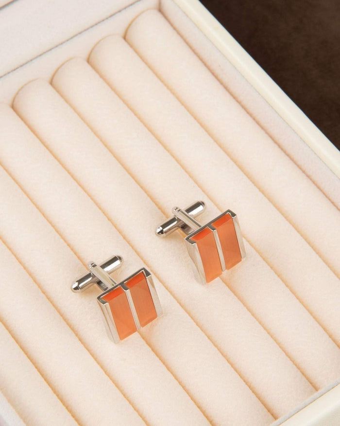 Rectangular silver cufflinks with orange dual stripe inlay in open tray