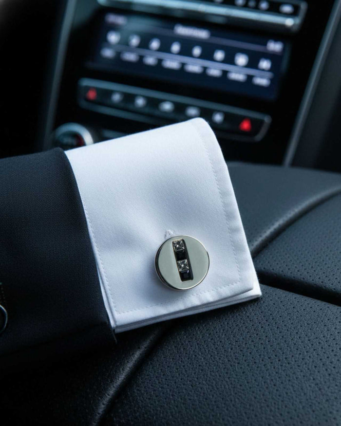 Round silver-tone cufflinks on a white dress shirt cuff, single pair