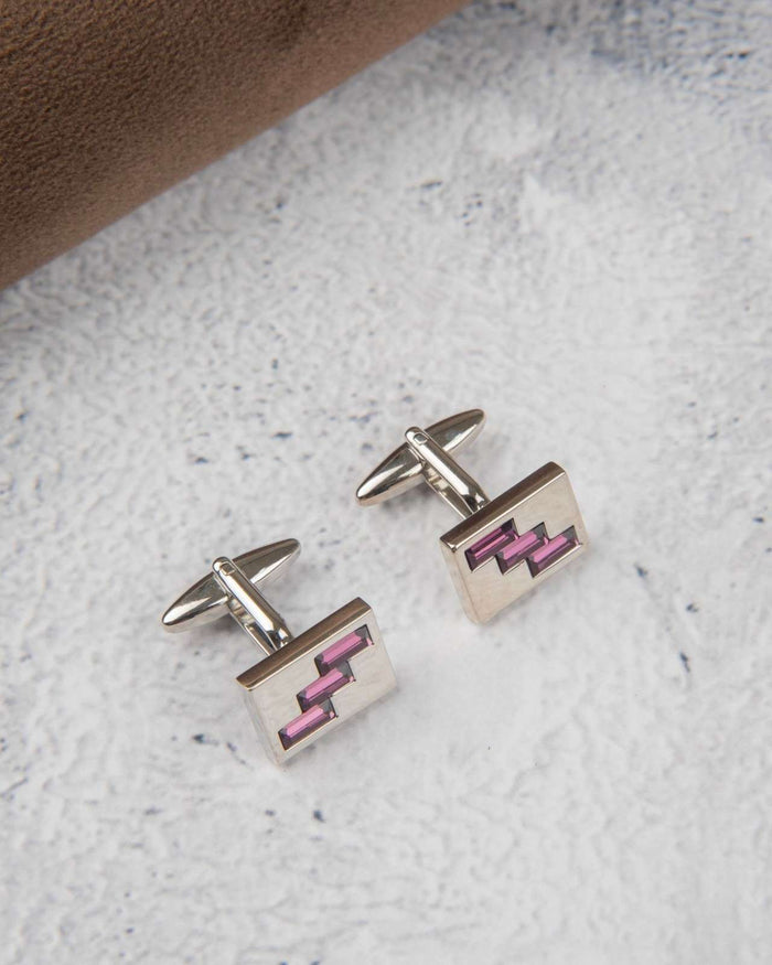 Close-up of silver cufflinks with pink zigzag crystal inlay in square frames