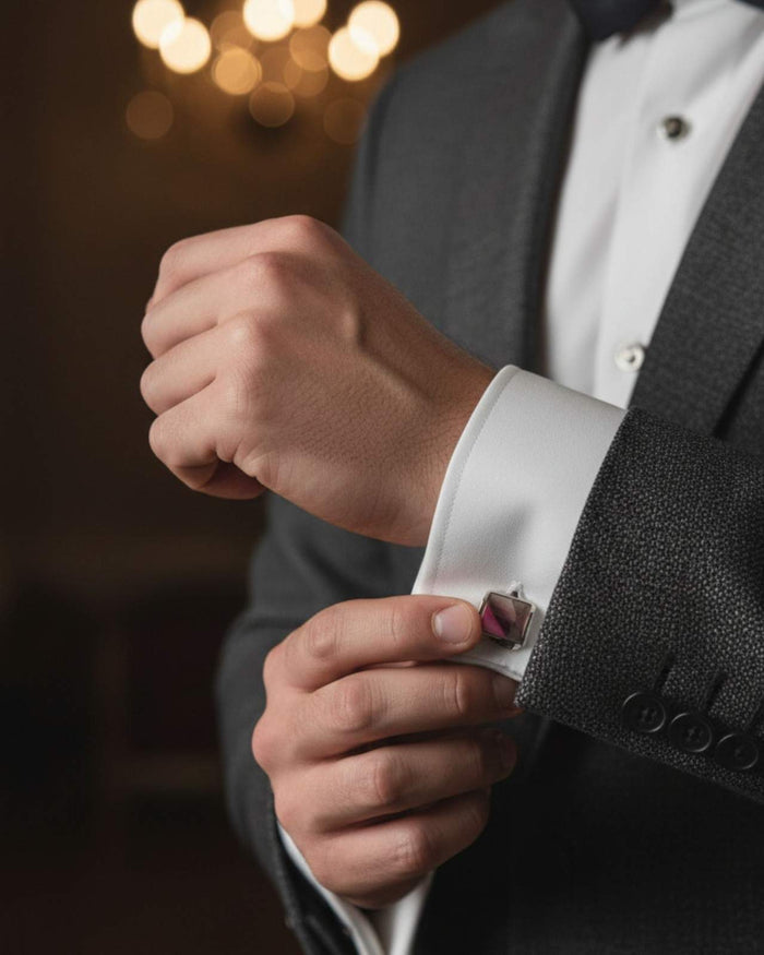 Silver-tone cufflinks with pink cylinder ends, worn at shirt cuff