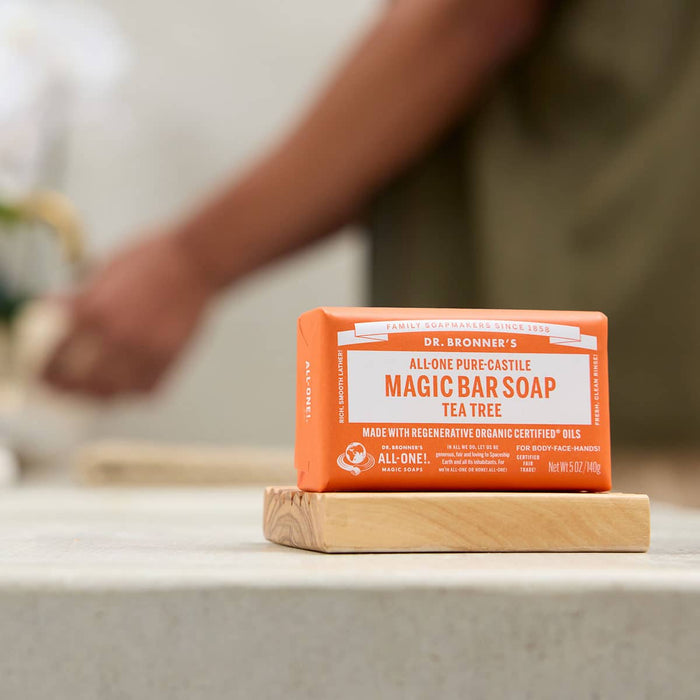 Dr. Bronner's Pure-Castille Magic Soap Bar - Tea Tree 140g on a wooden stand with a blurred background.