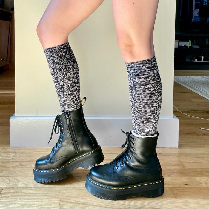 Knee-high compression socks in a black and white spacedye pattern worn with black lace-up boots.