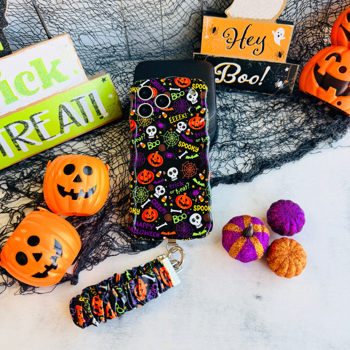 Spooky scrunchie phone wrist strap and matching Wavy Luxe case styled together with a Hey Boo sign and orange jack-o-lantern pails.