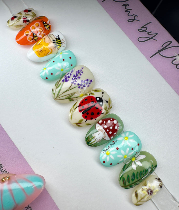 Colorful nail art designs on a white surface with 'Paws by Picasso branding.