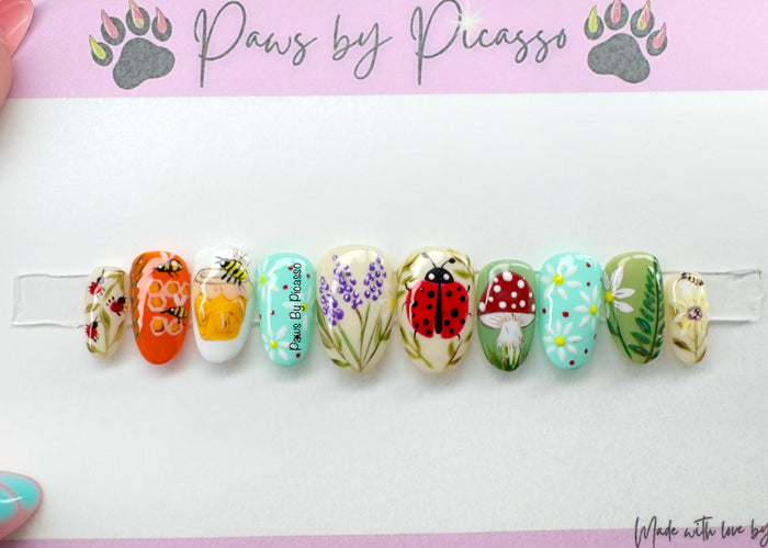 Decorative nail art clips with various designs on a white background, branded 'Paws by Picasso'.