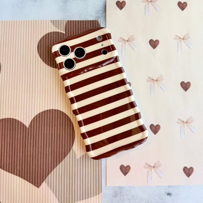 Sweet Espresso Stripes Wavy Luxe MagSafe iPhone case flat lay on brown heart and bow paper, showing the full striped print and the sculpted wavy edge.