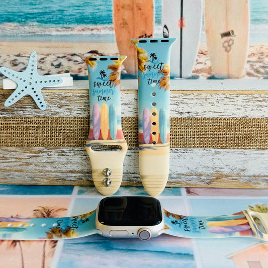 Sweet Summer silicone Apple Watch band with pastel pink, yellow, and blue surfboards, palm trees, and "sweet summer time" script on a soft watercolor beach scene, shown displayed and worn on Apple Watch against a coastal surfboard backdrop.