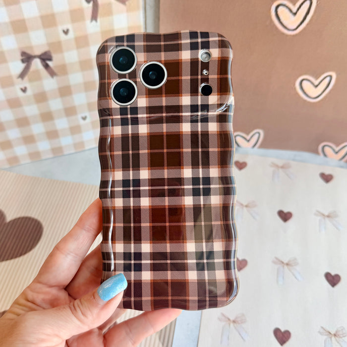 Hand holding the Toffee Tartan Wavy Luxe MagSafe iPhone case, showing the brown, cream and black tartan plaid print.