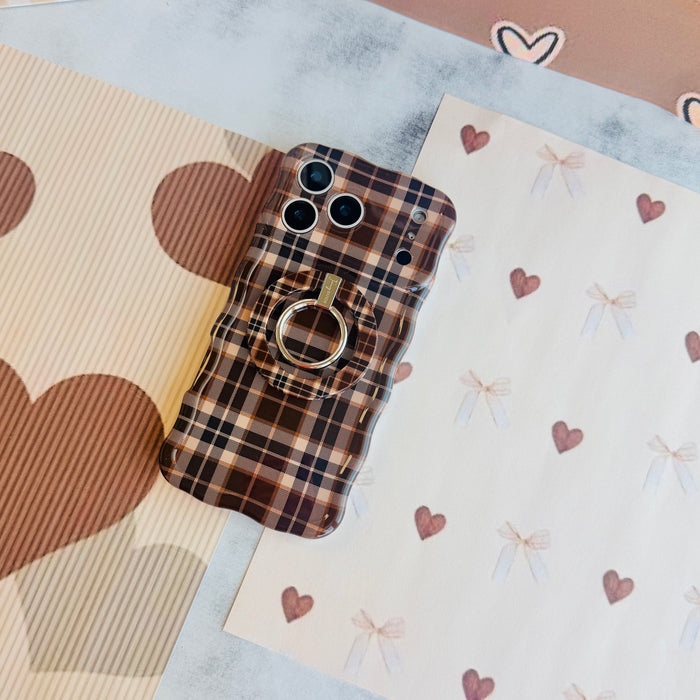 Toffee Tartan Wavy Luxe iPhone case with the matching MagSafe grip ring attached, styled on cream bow and brown heart paper.