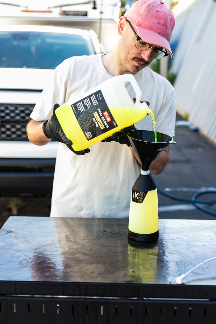 Person pouring liquid from a gallon jug of P&S Undressed into a funnel on an iK Sprayer.