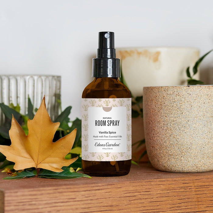 Room spray bottle labeled 'Vanilla Spice' by Edens Garden on a wooden surface with leaves and a pot in the background.