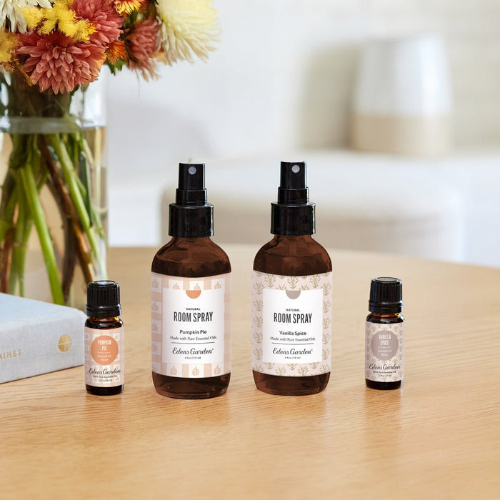 Set of room spray bottles on a wooden surface with flowers in the background